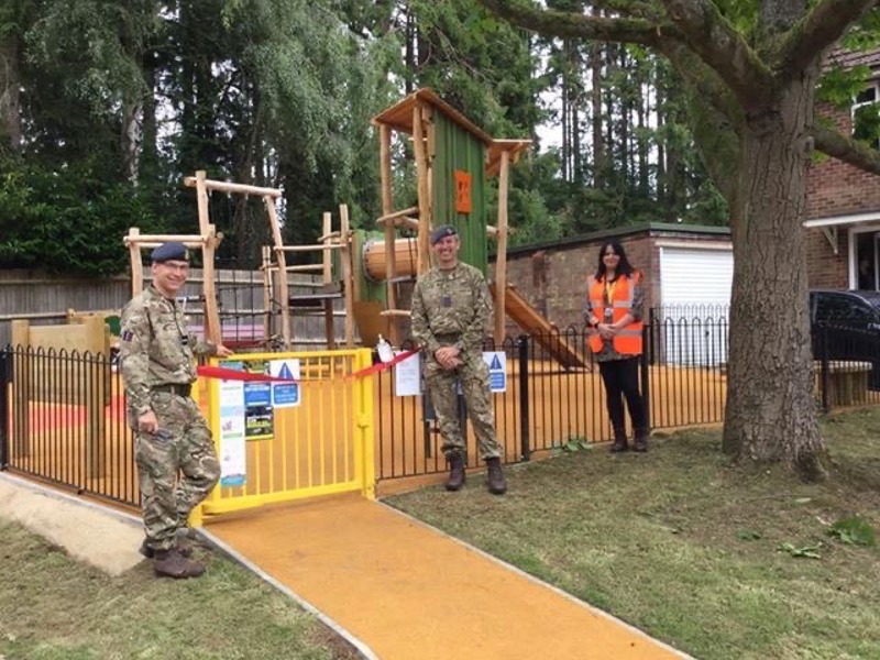 Image of military personnel stood in front of a children's play park.