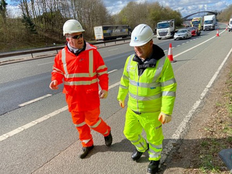 Two Amey employees in PPE chatting at the roadside.