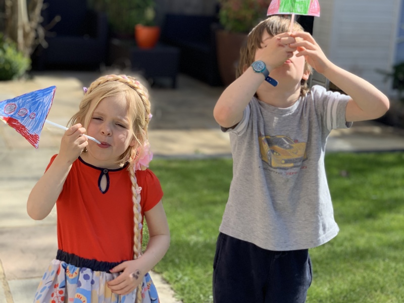 Two children playing with pictures of rocket ships attached to straws.