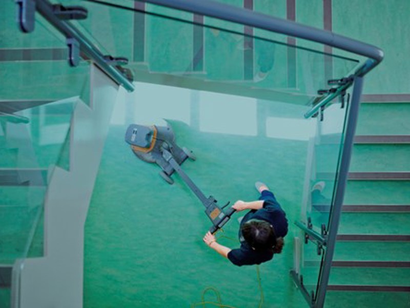 ariel image of a person cleaning the floor at the bottom of a stairway.