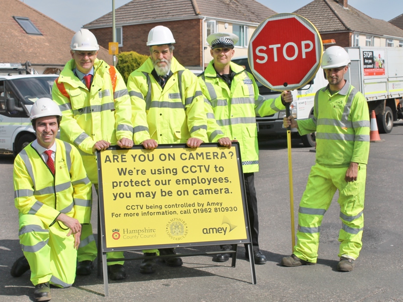 Five men in PPE holding a stop sign.