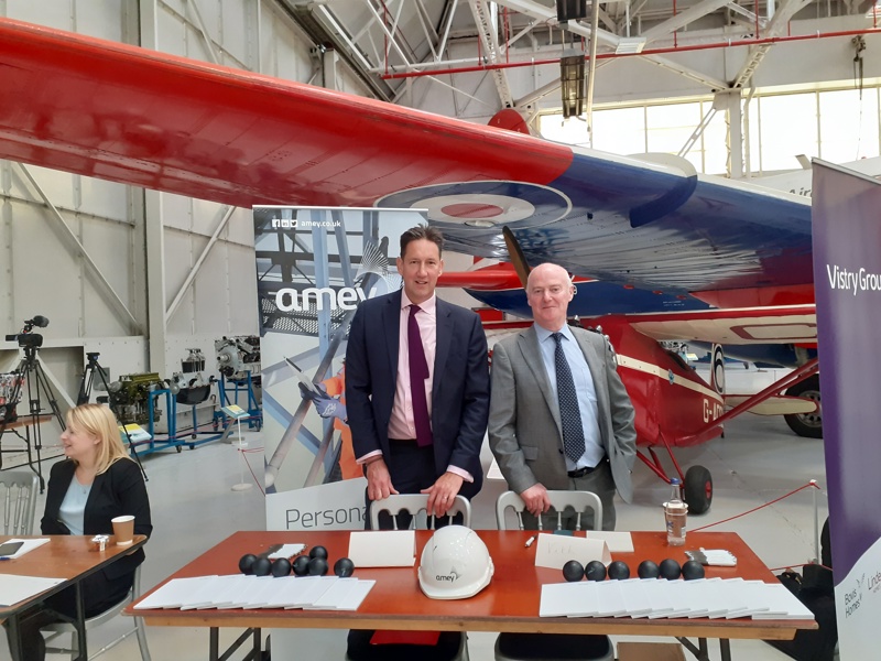 Two Amey employees standing at a table, in front of a RAF plane.