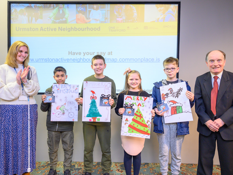 Image of Amey employees, stood with children holding Christmas pictures they've drawn.