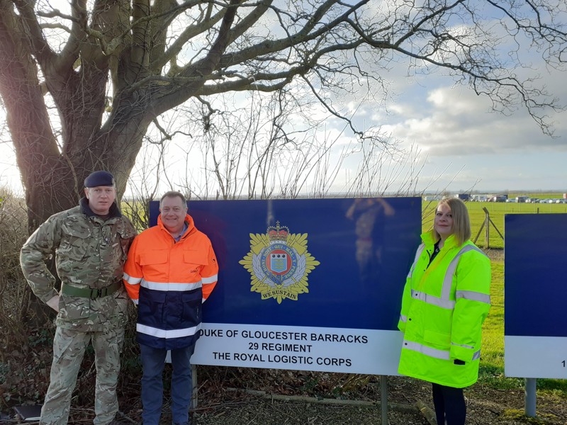 Image of Amey and military personnel in front of the Duke of Gloucester Barracks sign.