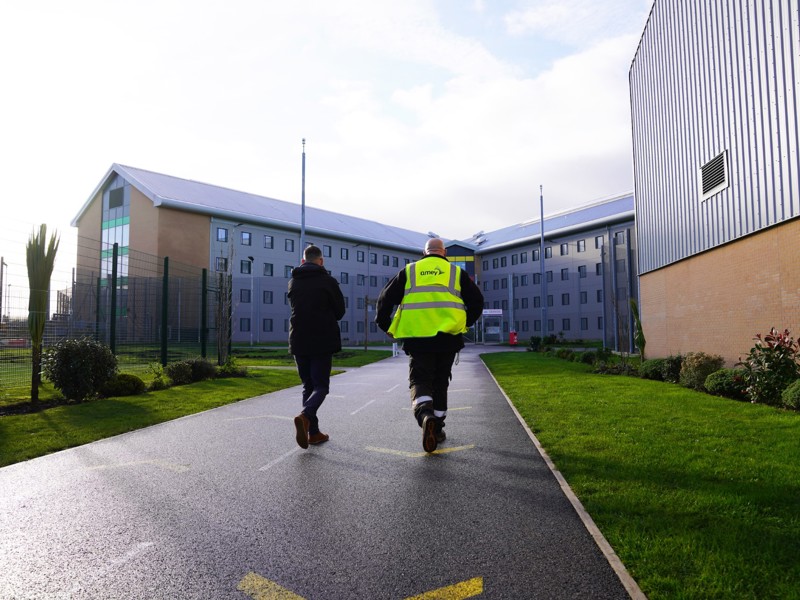 Image of two Amey employees walking up to a building along a path.