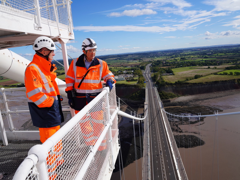 Image of two men in PPE, looking over metal railing.