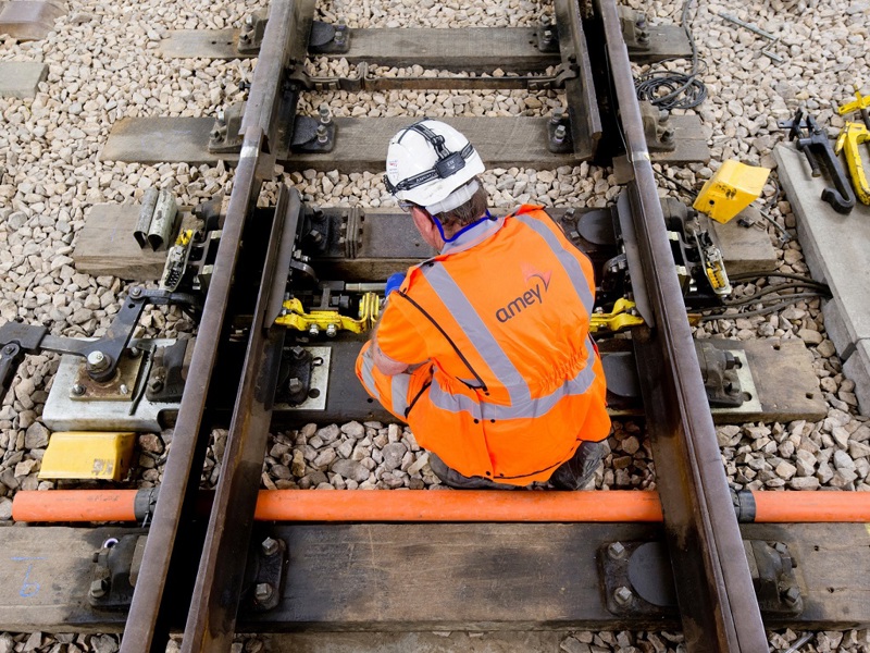 A man in PPE, carrying out rail maintenance. 