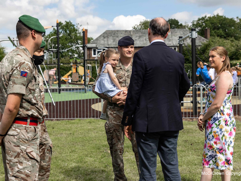 Military family stood in front of a children's playground. 