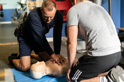 Two men undertaking CPR training on a dummy