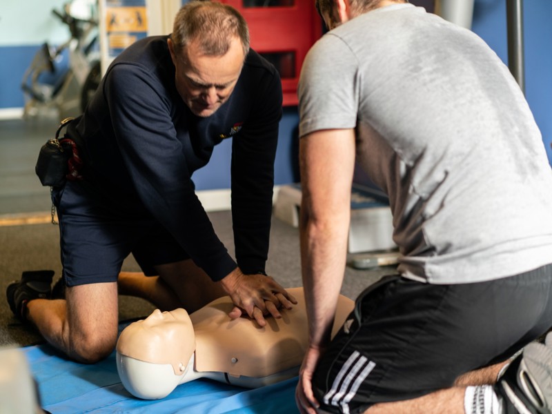 Two men undertaking CPR training on a dummy