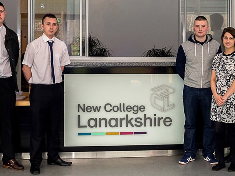 Group picture of people stood in front of New College Lanarkshire reception.