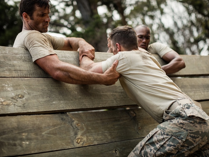 Image of military men climbing over a wooden structure.