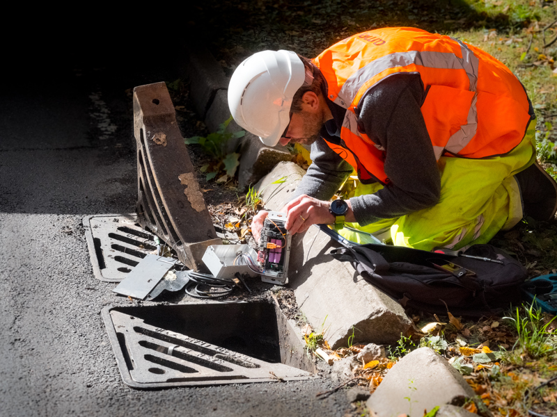 An Amey employee in PPE, carrying out an inspection of a drain.