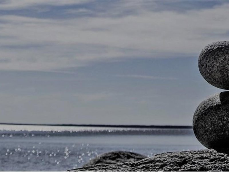Image of two pebbles balancing on top of each other at a beach.