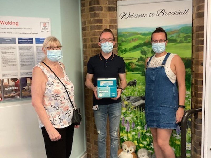 Image of three Amey employees, wearing face masks, stood in front of a 'Welcome to Brockhill' sign.