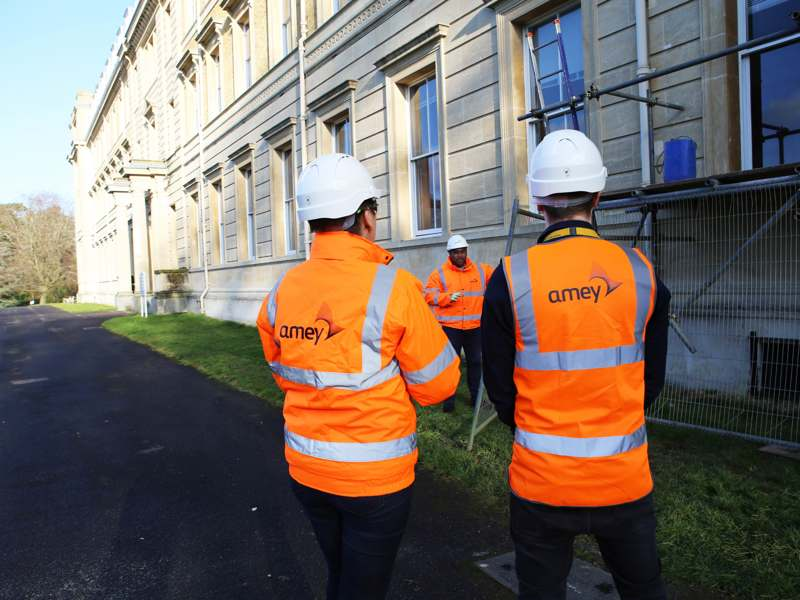Image of Amey employees in PPE stood in front of a building with scaffolding.