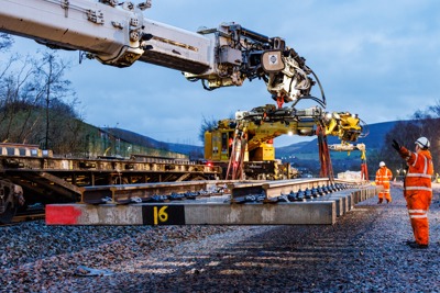 A crane lowering a rail sleeper