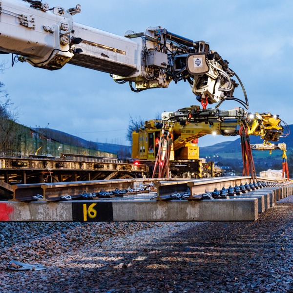 A crane lowering a rail sleeper