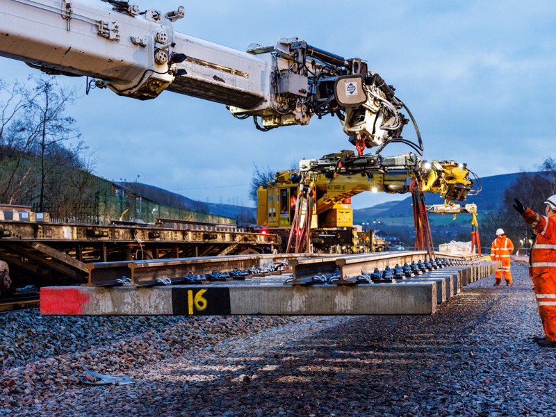 A crane lowering a rail sleeper