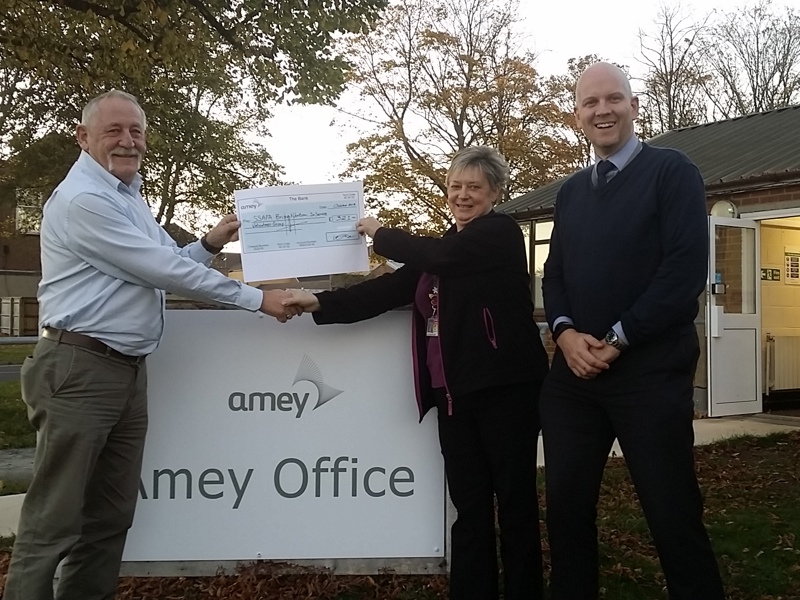 Image of Amey and RAF personnel holding a cheque, shaking hands as Amey supports 10th anniversary of Brizefest.