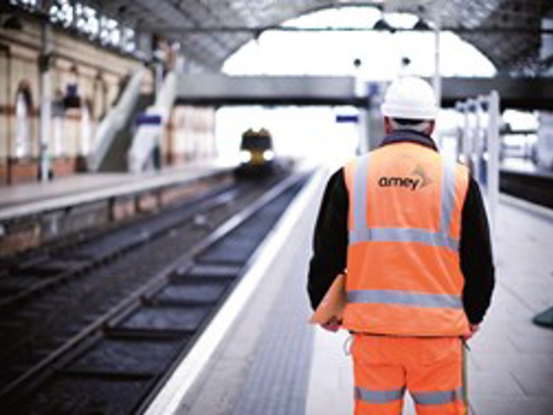 Image of an Amey employee, stood at an empty rail platform.