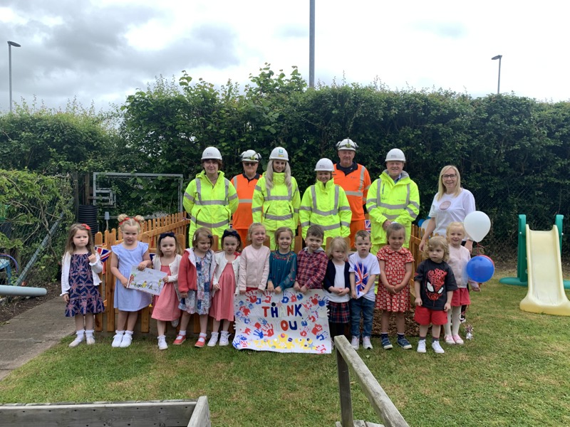 Image of Amey employees in PPE, with children holding a thank you banner.