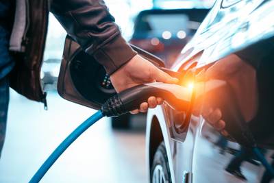 Image of a man placing a charger in an electric car.