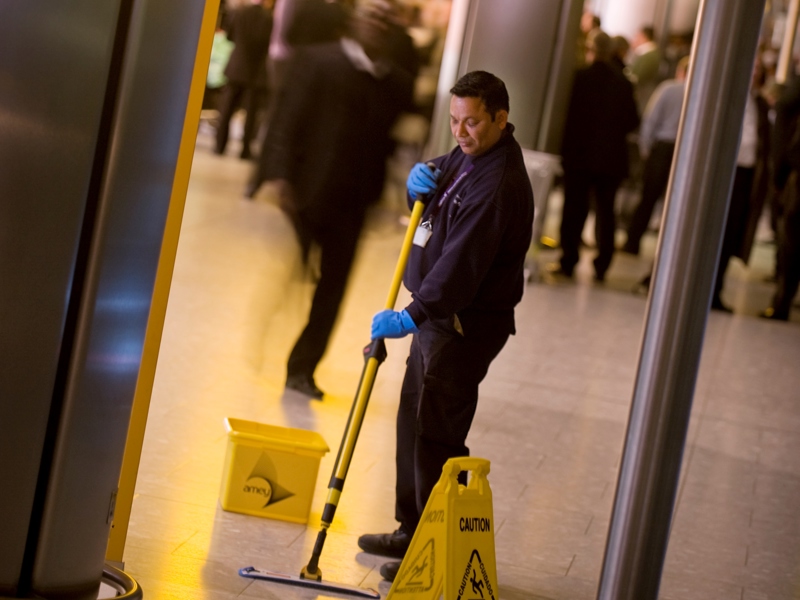 Image of a male Amey employee, cleaning the floor with a mop.