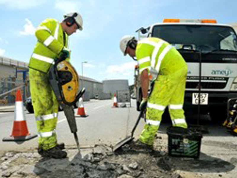 Image of two men in PPE, carrying out a pot hole repair.