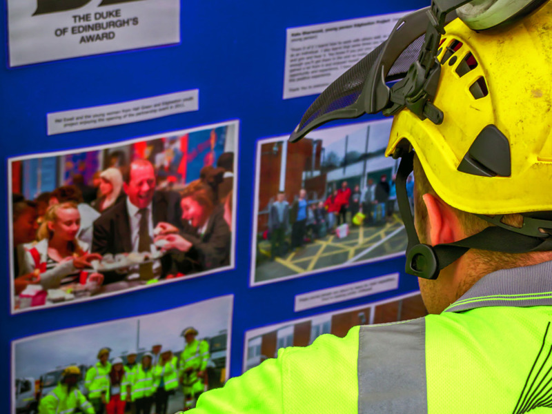 Image of man in PPE, looking at a notice board.