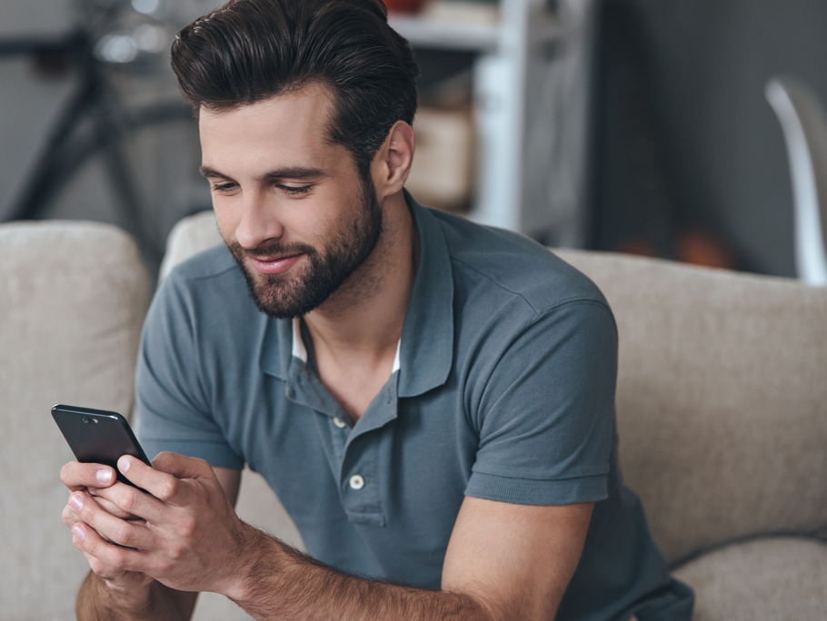 A man smiling, looking at a mobile phone