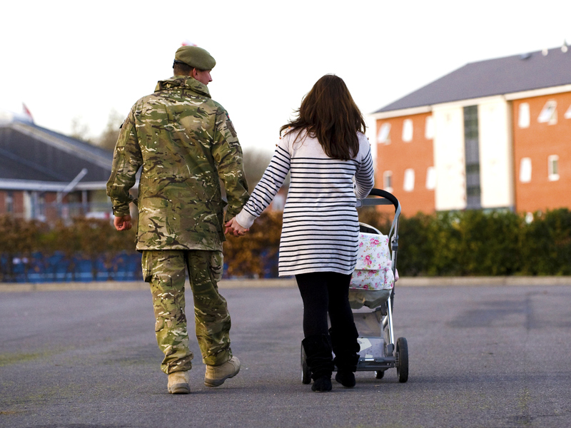 Image of a man wearing military uniform and a woman pushing a pram.