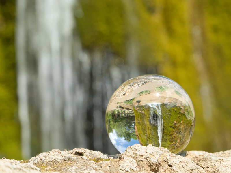 a glass sphere, in front of a waterfall.
